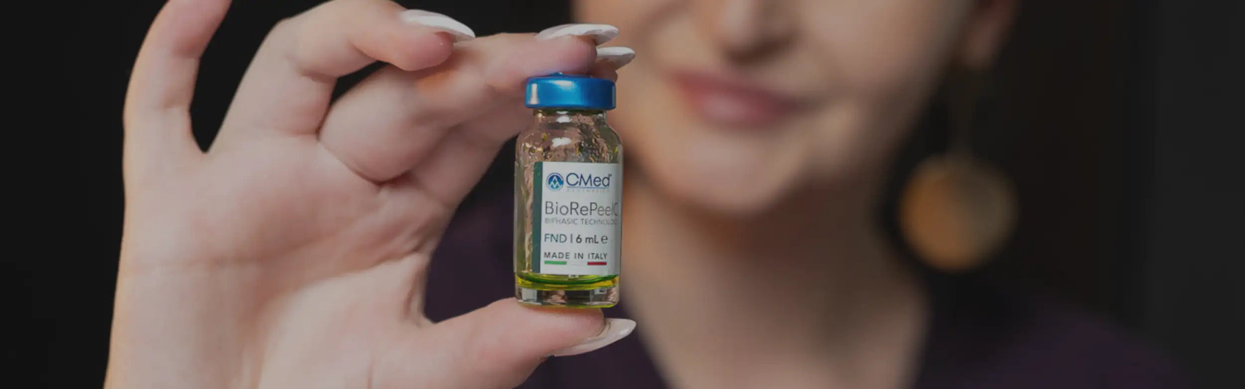 A small glass vial with a blue cap and white label, containing a yellowish liquid.