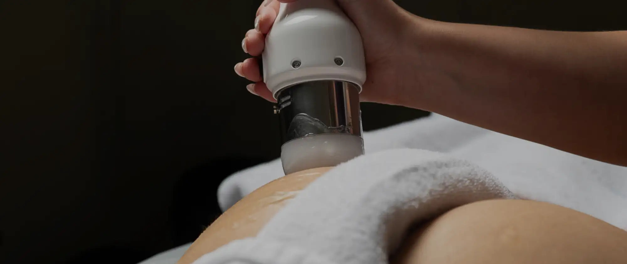 White cylindrical massage device with metallic accents being held over a person’s lower back